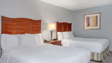 A hotel room with two beds, a nightstand with a lamp, and a framed picture on the wall.