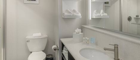 A modern bathroom with a toilet, sink, and towel racks.
