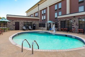 A swimming pool with a stone wall and a metal ladder. - Hampton Inn South Hill (South Hill)