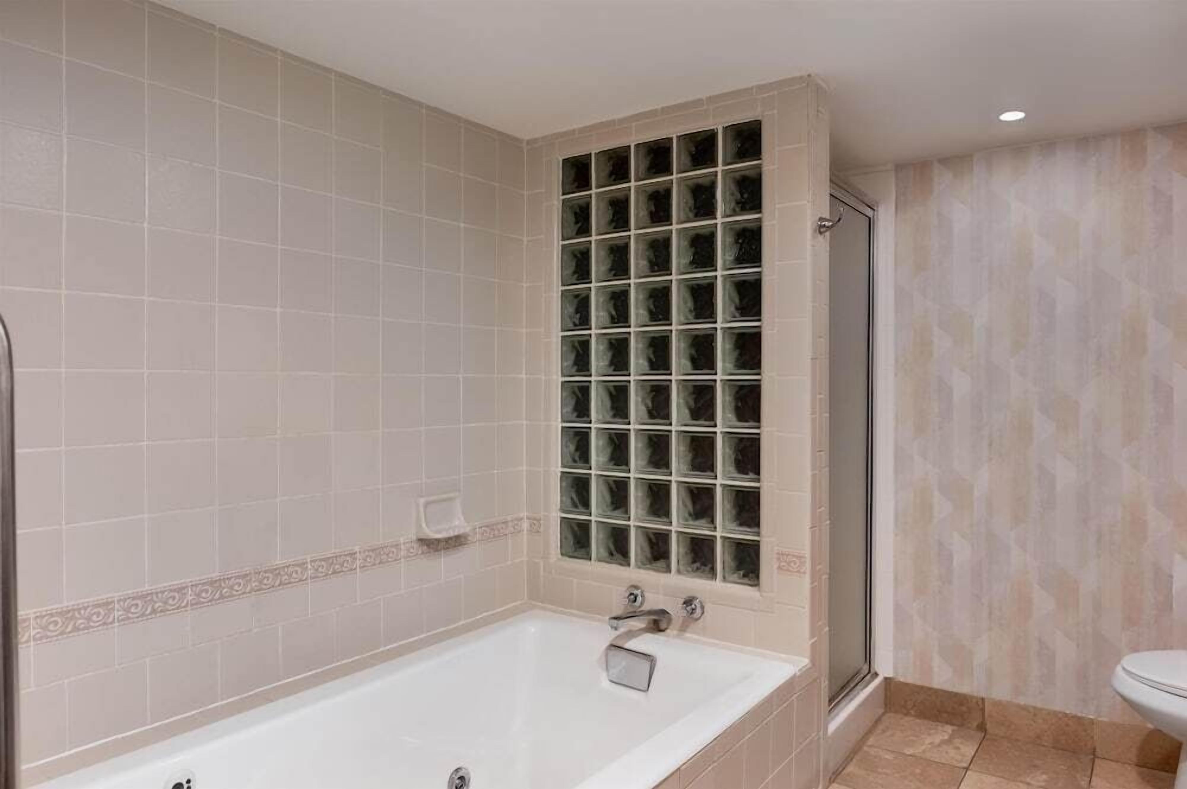 Un baño con bañera, cabina de ducha de vidrio y retrete.