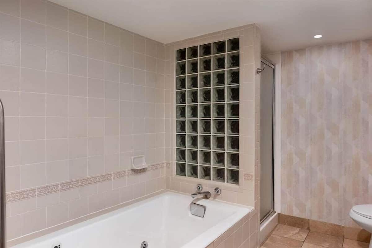 A bathroom with a bathtub, a glass shower enclosure, and a toilet.
