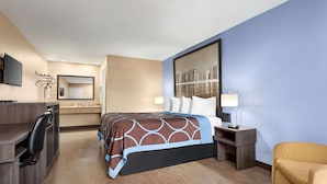 A hotel room with a bed, desk, chair, and a large mirror.