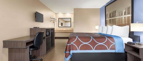 A hotel room with a bed, desk, chair, television, and a large mirror.