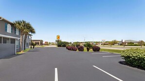 A parking lot with a gas station in the distance, surrounded by buildings and greenery.