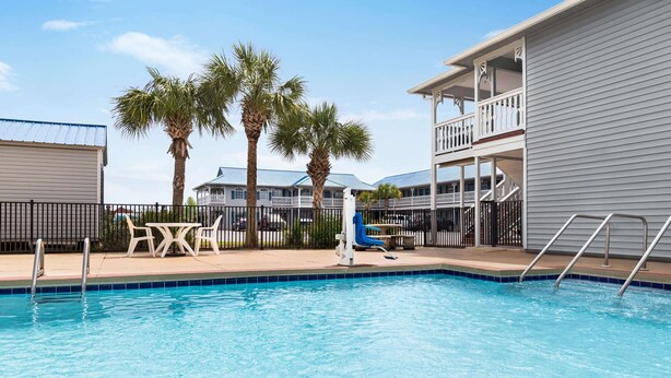 A swimming pool with a slide, palm trees, and a building with a balcony.