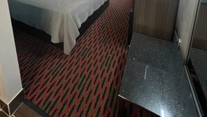 A hotel room with a bed, a desk, a chair, a TV, and a window with curtains. - Keywest Inn - Tuscumbia/Muscle Shoals (Tuscumbia)