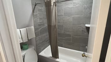 Ein Badezimmer mit Toilette, Badewanne und Duschvorhang.