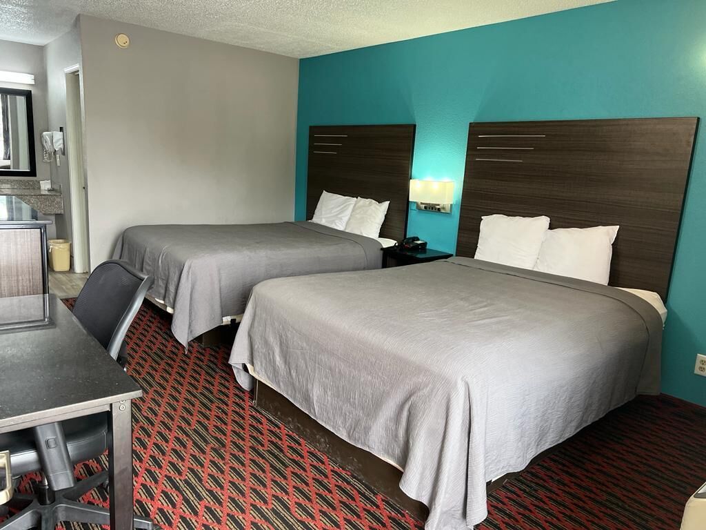 A hotel room with two beds, a desk, and a chair.