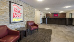 A Red Roof Plus hotel lobby with leather chairs, a reception desk, and a sign indicating free Wi-Fi in all rooms. - Red Roof Inn PLUS+ & Suites Opelika (Opelika)