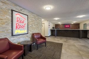 Hall de un hotel Red Roof Plus con sillones de cuero, un mostrador de recepción y un letrero que indica Wi-Fi gratuito en todas las habitaciones.