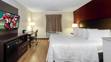 A hotel room with a bed, desk, chair, television, and a window with curtains.