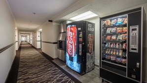 A hotel corridor with vending machines, including a Coca-Cola cooler and a snack dispenser. - Red Roof Inn PLUS+ & Suites Opelika (Opelika)