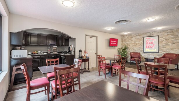 A hotel room with a kitchenette, dining area, and a sign indicating free Wi-Fi availability. - Red Roof Inn PLUS+ & Suites Opelika (Opelika)