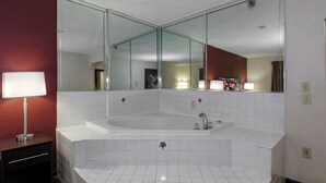 Un baño con una bañera grande, un espejo y un tocador con una lámpara.