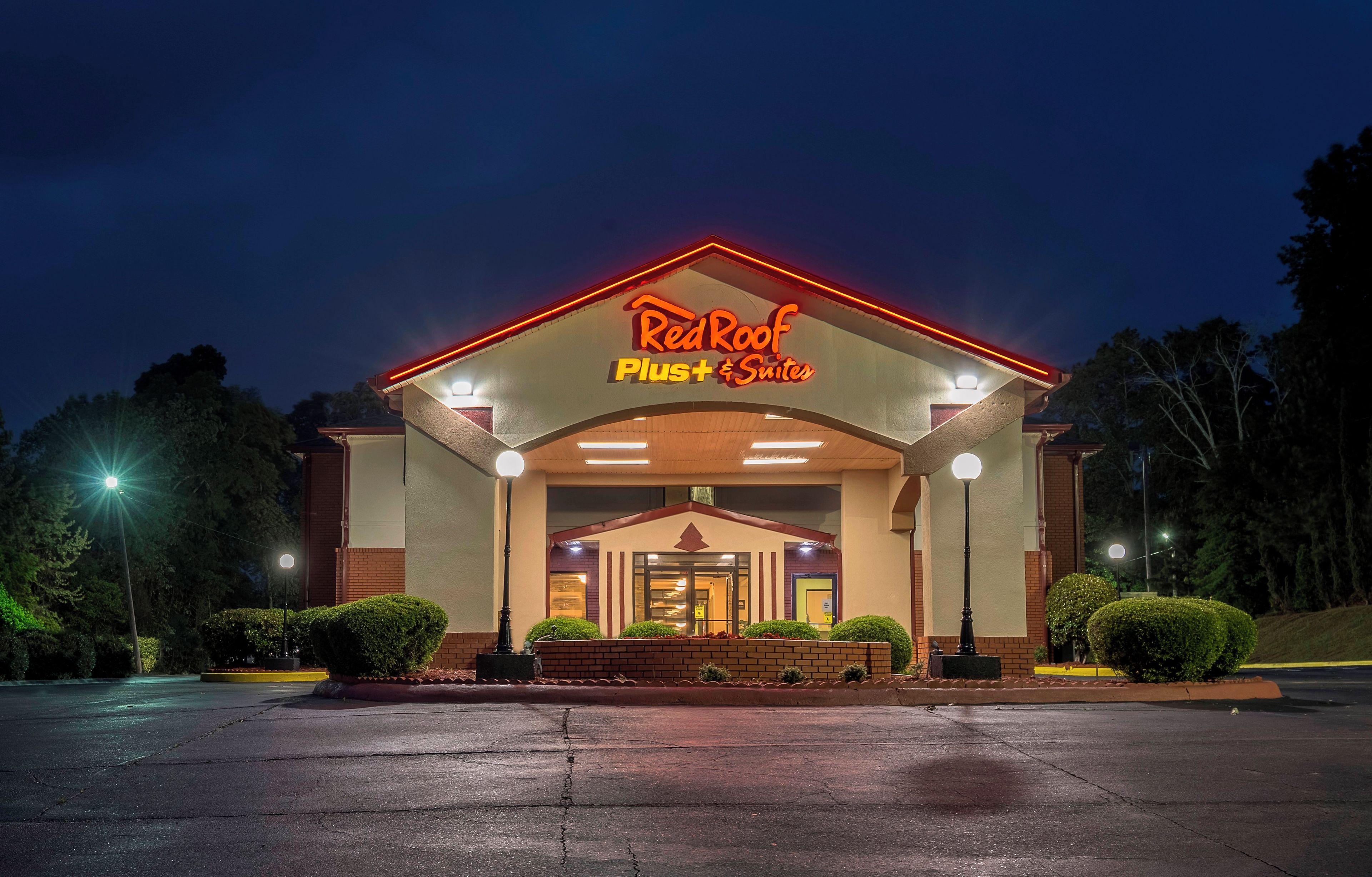 A hotel entrance with a sign reading 'RedRoof Plus Suites' and a covered walkway.