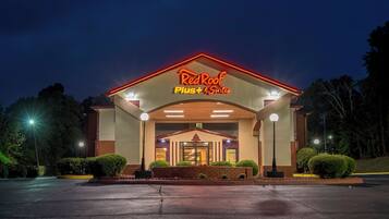 A hotel entrance with a sign reading 'RedRoof Plus Suites' and a covered walkway.
