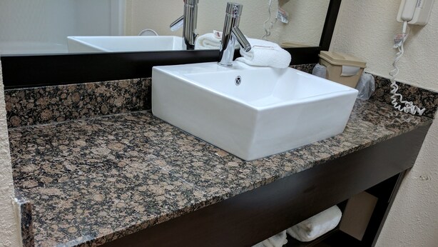 Un baño con encimera de granito, un lavabo blanco y un inodoro.