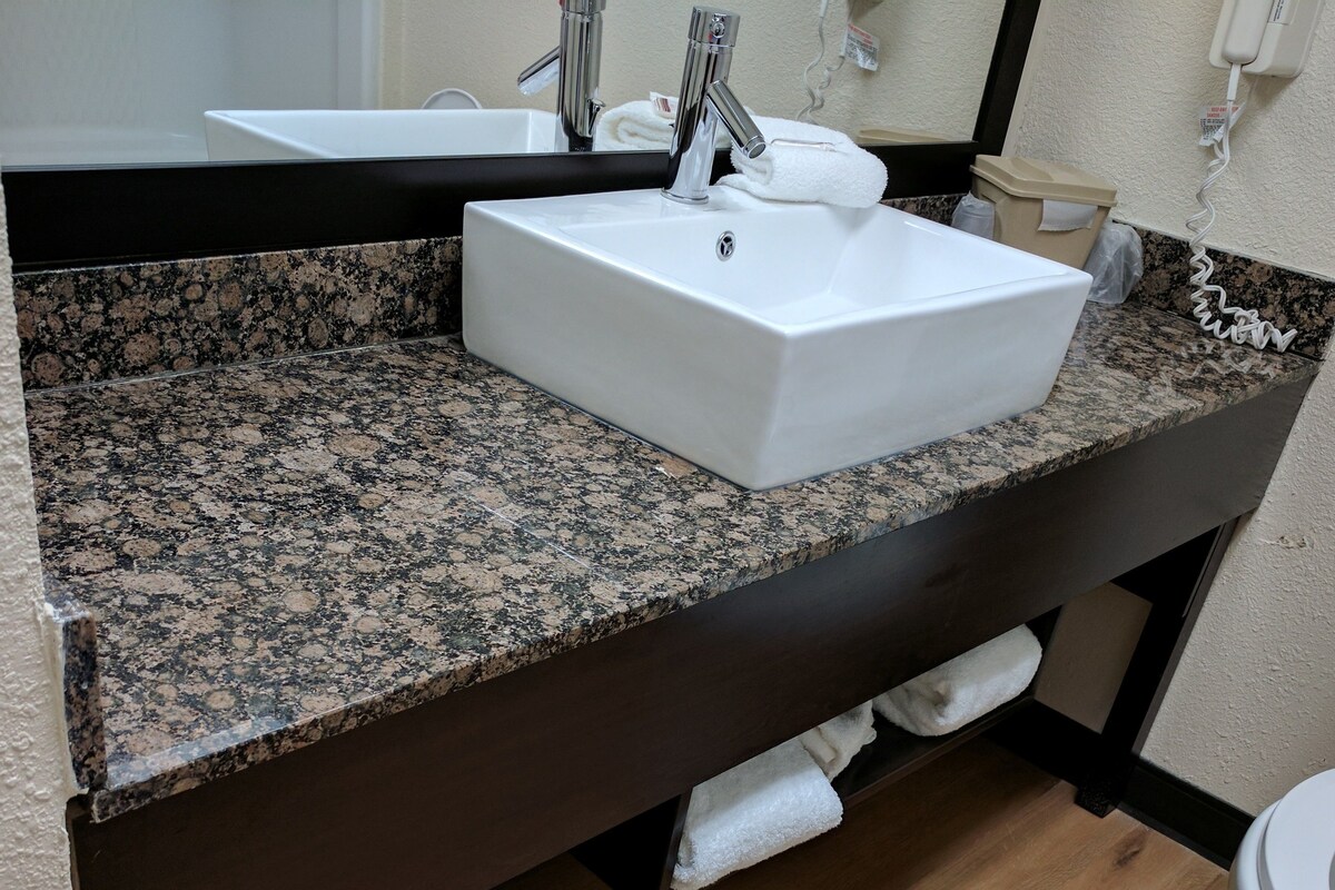 A bathroom with a granite countertop, a white sink, and a toilet.