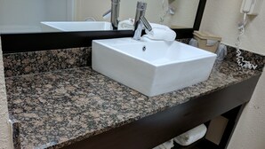 A bathroom with a granite countertop, a white sink, and a toilet. - Red Roof Inn PLUS+ & Suites Opelika (Opelika)