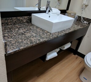 A bathroom with a granite countertop, a white sink, and a toilet. - Red Roof Inn PLUS+ & Suites Opelika (Opelika)