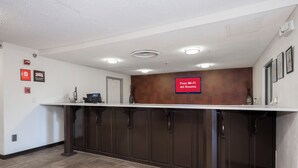 A reception area with a counter, a fire alarm, and a sign indicating free Wi-Fi in all rooms. - Red Roof Inn PLUS+ & Suites Opelika (Opelika)