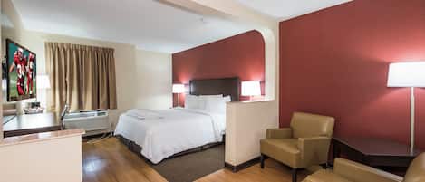 A hotel room with a bed, two bedside lamps, a desk with a chair, a TV, and a window with curtains.