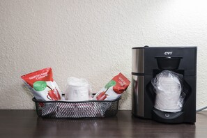 A coffee machine and a basket with coffee pods and a plastic bag. - Red Roof Inn PLUS+ & Suites Opelika (Opelika)