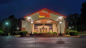 Entrada de un hotel con un letrero que dice 'RedRoof Plus Suites' y un vestíbulo techado.