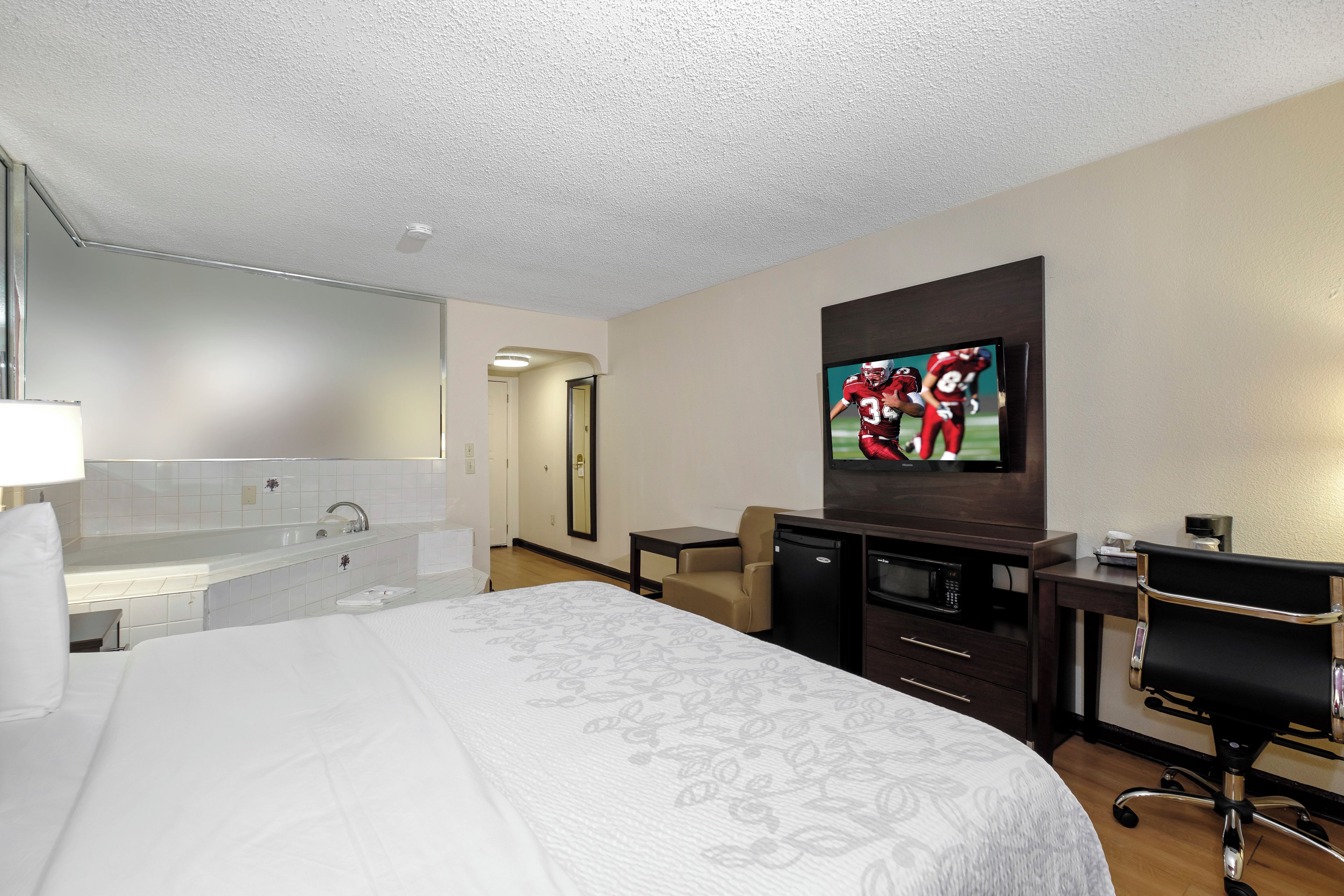 A hotel room with a large bed, a TV, a desk, and a chair.