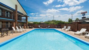 A swimming pool with lounge chairs, a brick building, and a clear sky. - Days Inn by Wyndham Clanton AL (Clanton)