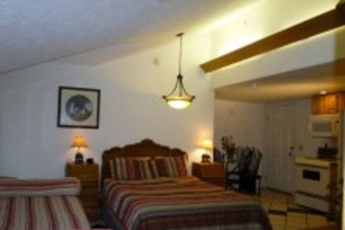 Une chambre à coucher avec un lit, des tables de chevet, une lampe et un tableau encadré au mur.