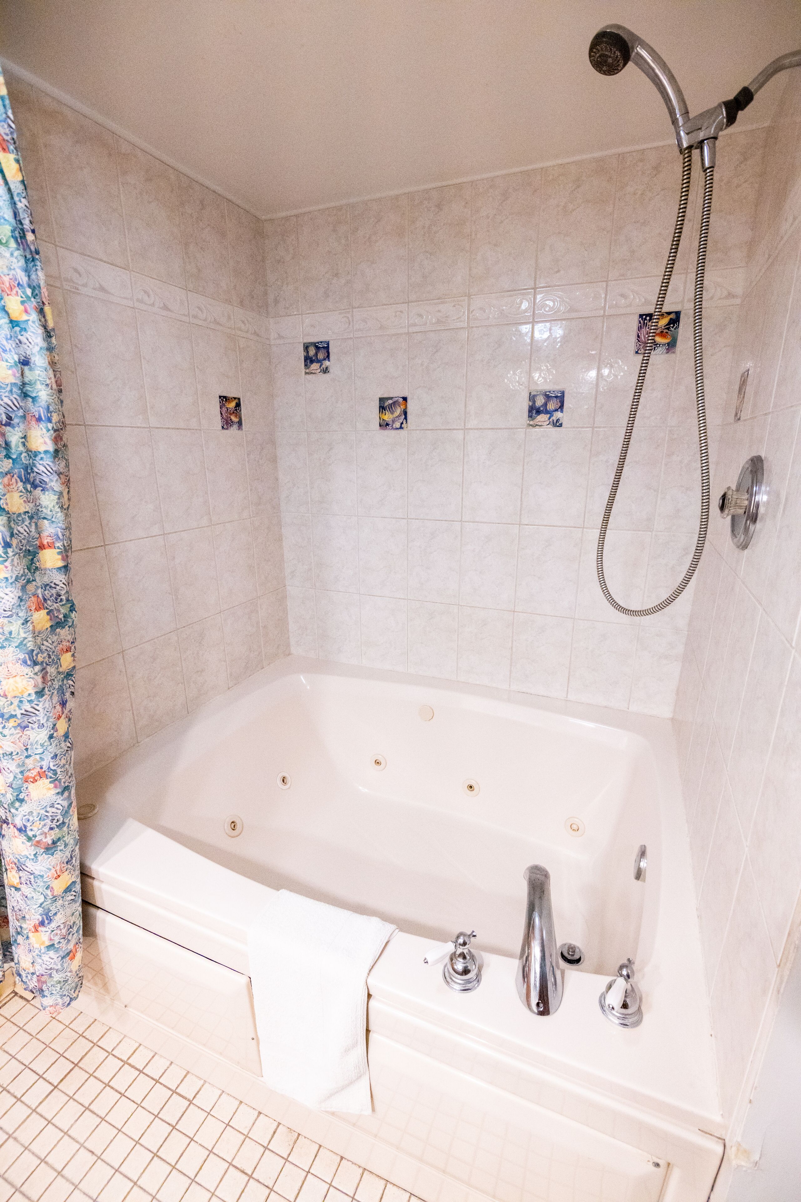 A bathroom with a bathtub, shower, and tiled walls.