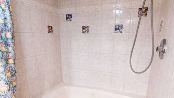 A bathroom with a bathtub, shower, and tiled walls.