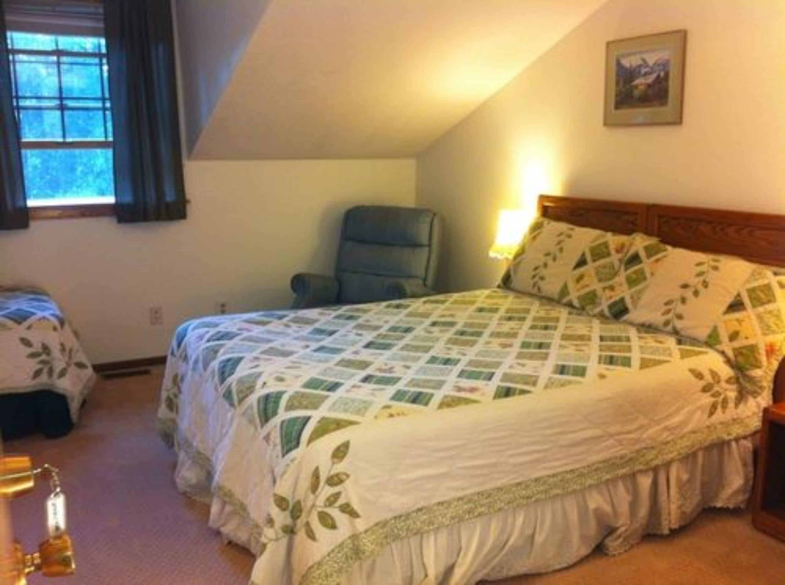 A bedroom with a bed, a chair, and a window.