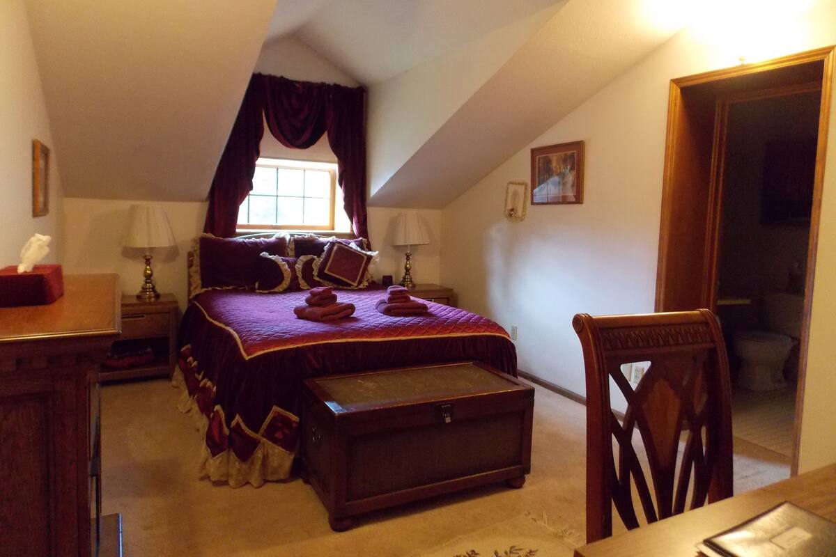 Une chambre à coucher avec un grand lit, une commode en bois, un bureau et une chaise.