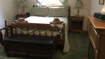 A bedroom with a bed, a bench, a nightstand, a lamp, and a dresser.