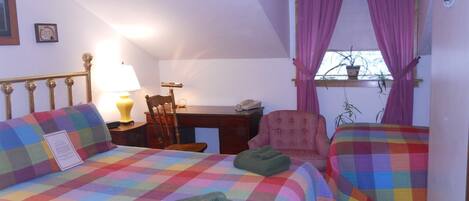 Une chambre avec deux lits, un bureau, une chaise et une fenêtre avec des rideaux.
