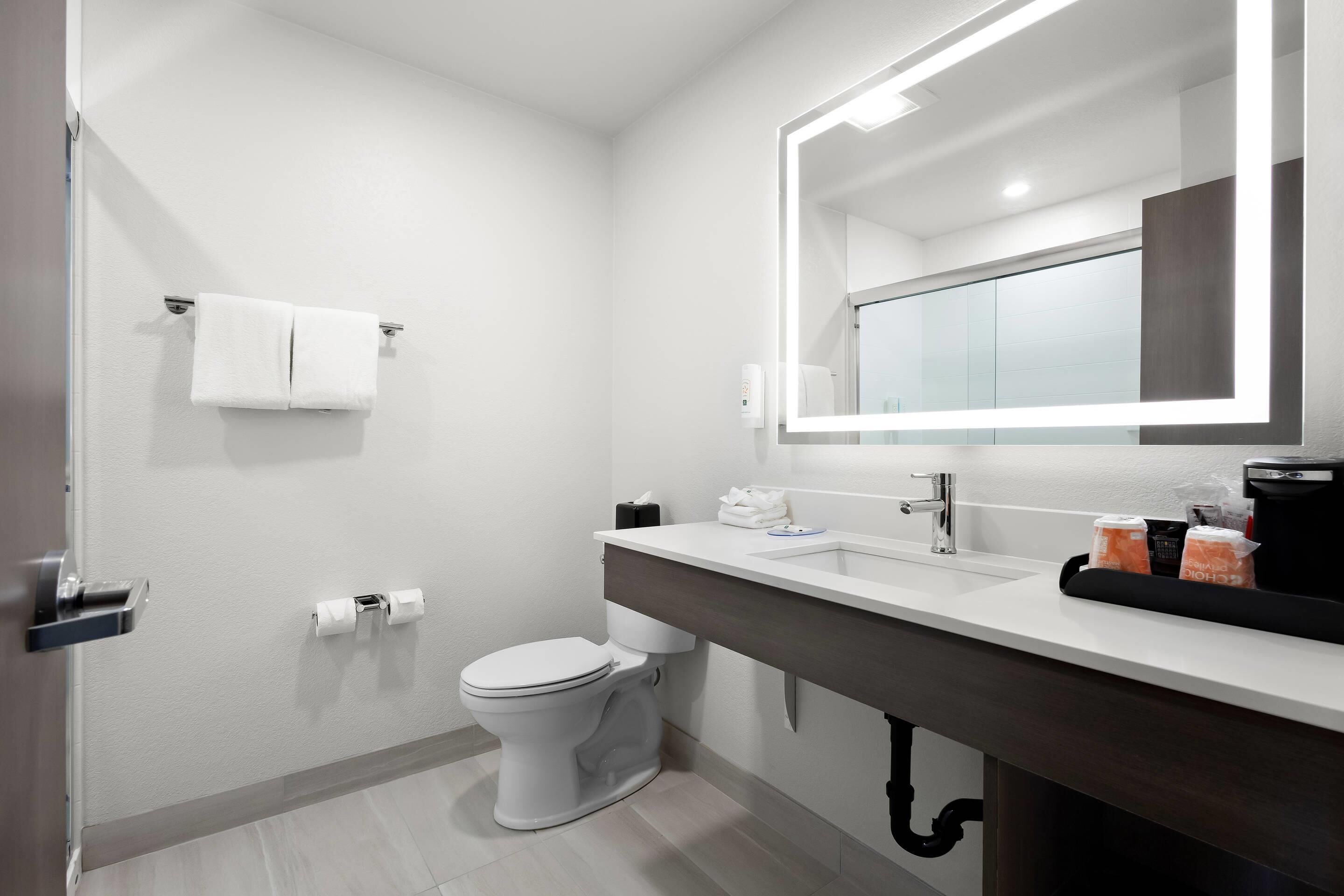 A modern bathroom with a white toilet, a sink with a mirror, and a towel rack.