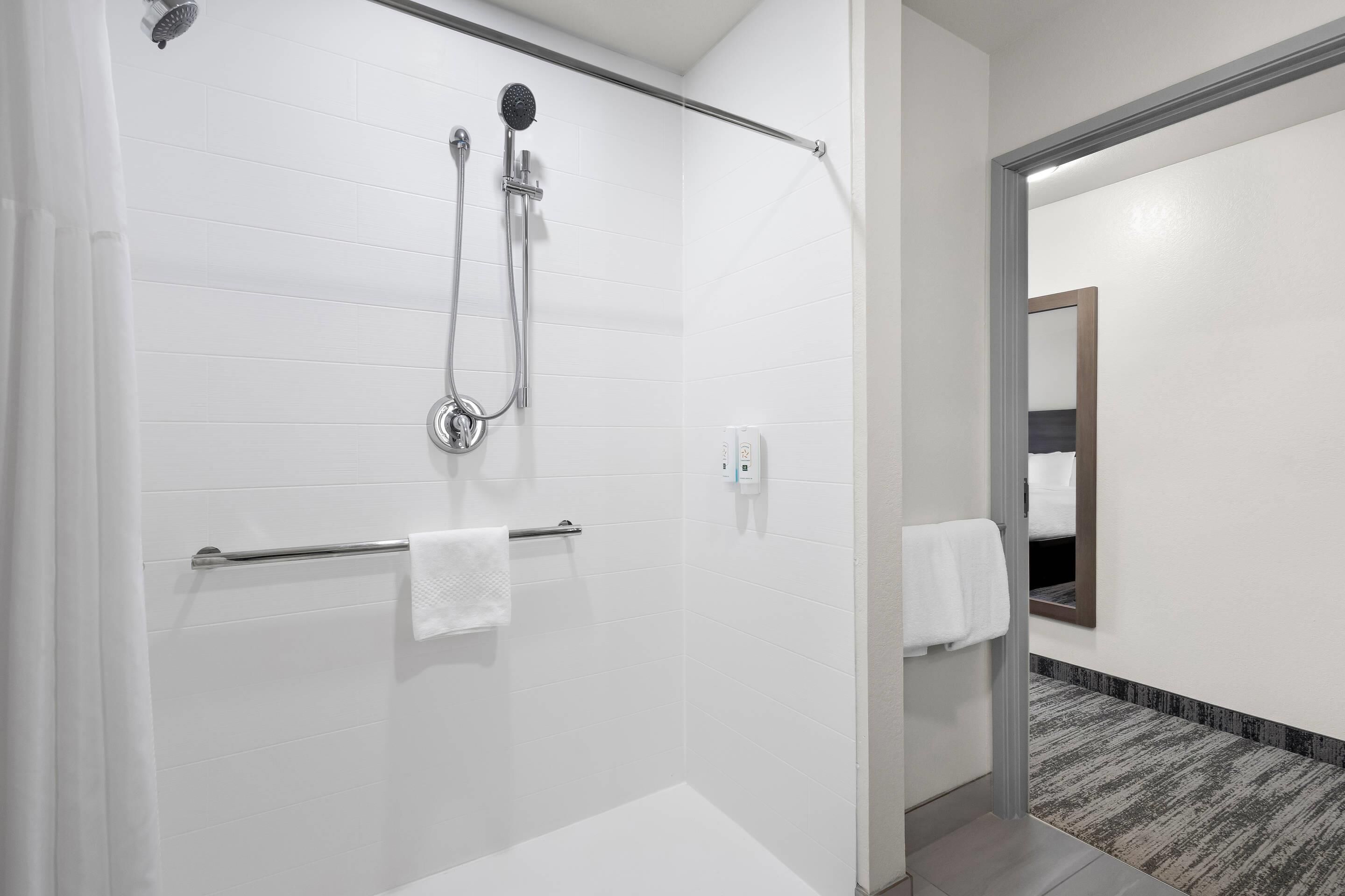 A modern bathroom with a walk-in shower, a towel rack, and a mirror.