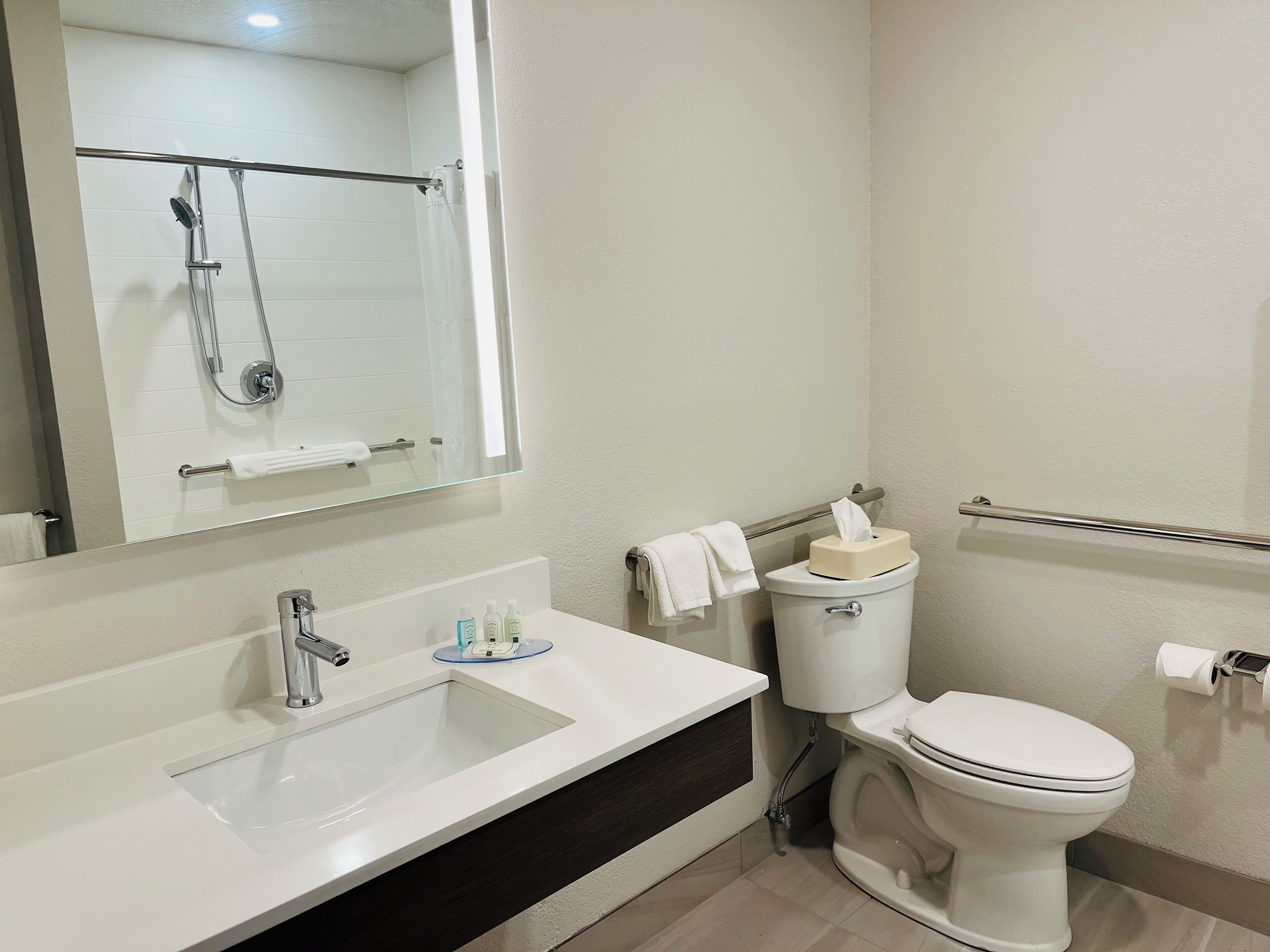 Un baño moderno con un lavamanos blanco, un espejo, un inodoro y una ducha.
