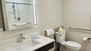 Un baño moderno con un lavamanos blanco, un espejo, un inodoro y una ducha.