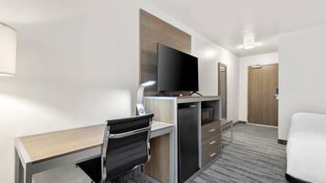 Habitación de hotel con escritorio, silla, televisor y cama.