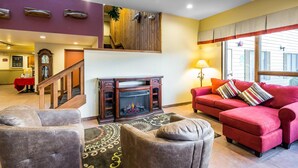 Una sala de estar con chimenea, un sofá rojo y dos sillones.