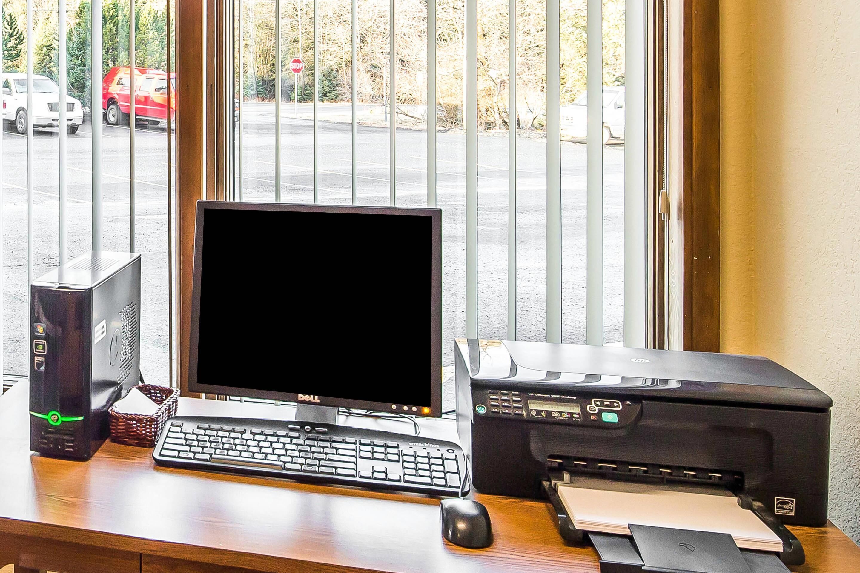 Et computerbord med en stationær computer, tastatur, mus og printer.
