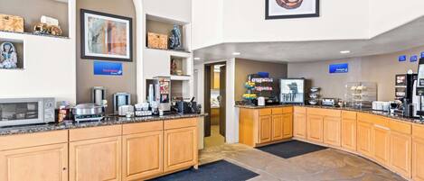 A modern kitchen with granite countertops, wooden cabinets, and a stone floor.
