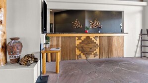 Una zona de recepción con mostrador de madera, televisión y decoración en la pared.