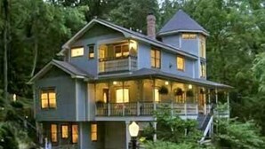 A two-story house with a balcony, surrounded by trees. - Arsenic and Old Lace B&B (Eureka Springs)