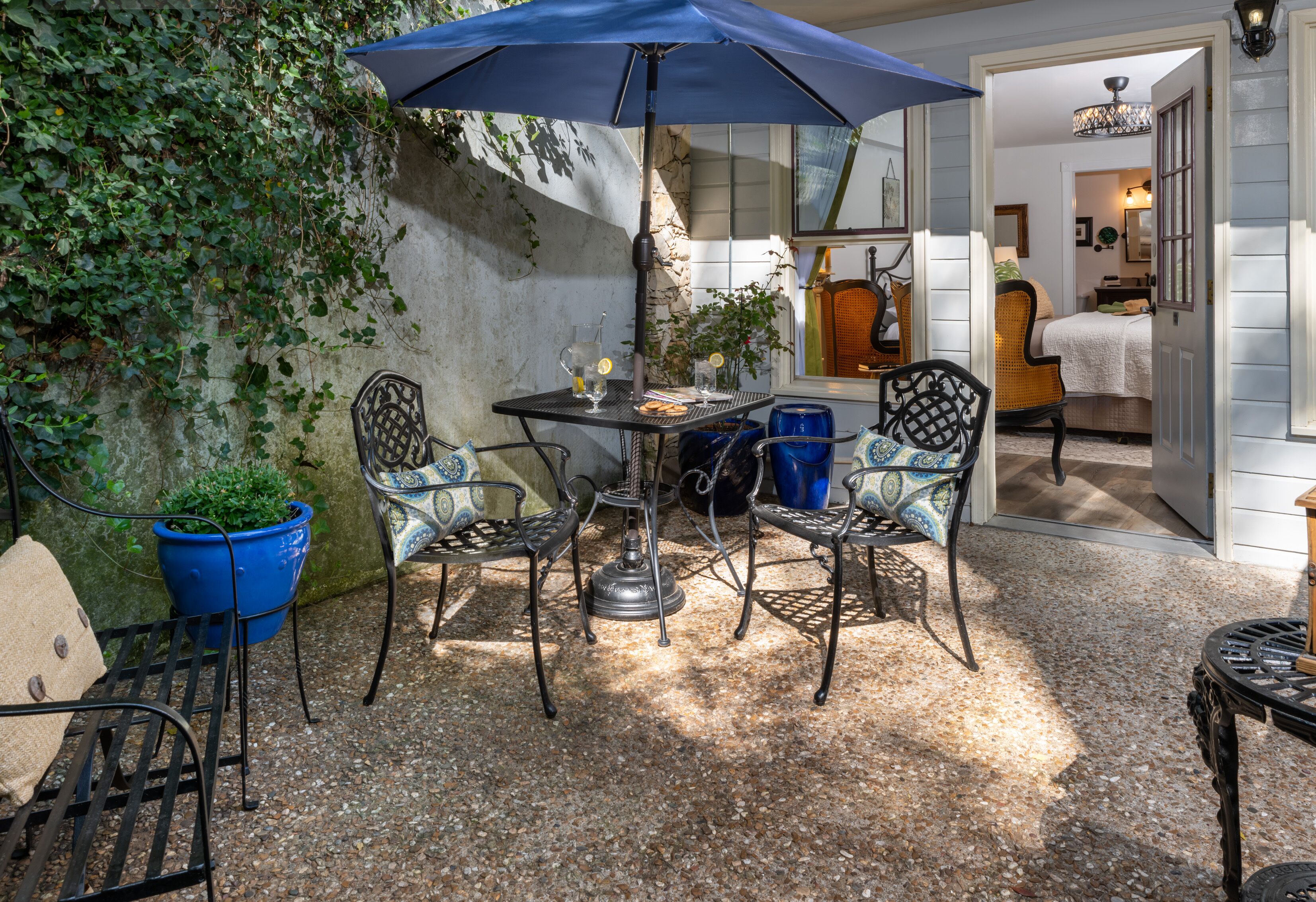 An outdoor patio with a table, chairs, and a blue umbrella.