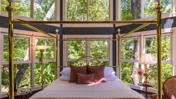 A spacious room with a large bed, a window with a view of trees, and a chandelier. - Arsenic and Old Lace B&B (Eureka Springs)