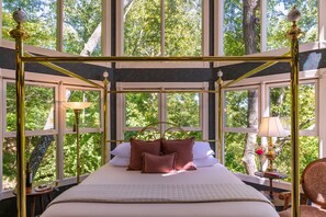 A spacious room with a large bed, a window with a view of trees, and a chandelier. - Arsenic and Old Lace B&B (Eureka Springs)